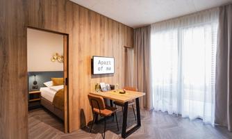 A cozy room with wooden paneling and a table. On it are several objects, and a large window lets in a lot of light.