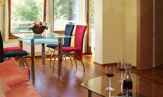 A bright living space with a table and colorful chairs. On the table, there are wine glasses and a flower vase.