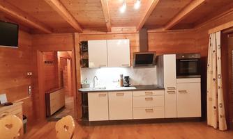 A modern kitchen in a wooden house with a wooden ceiling. It is well-equipped and has a bright, friendly atmosphere.
