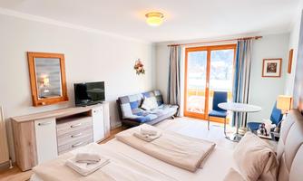 A cozy bedroom with two single beds and modern furniture. The room has a balcony with a view of nature.