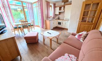 A bright and cheerful apartment with a cozy seating area and a small kitchen. Large windows provide plenty of natural light.