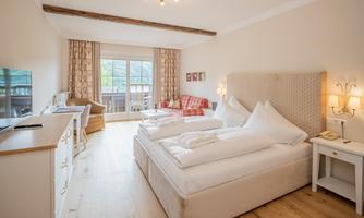 A cozy hotel room with a large bed, a television, and a beautiful view through the window. The modern decor and wooden floor create an inviting atmosphere.