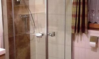 A modern bathroom with a glass shower. The walls are light tiled and there is a warm, inviting color tone.