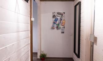 A bright hallway with a wooden floor and a wooden ceiling. On the left side, there is an orange seating area and a bulletin board.
