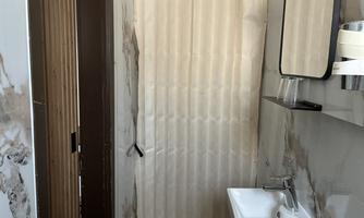 A simple bathroom with a shower curtain and a small sink. The walls are designed with a modern pattern.