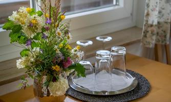 A stylish table decoration with fresh flowers in a vase and glasses on a tray. The scene conveys a cozy atmosphere.