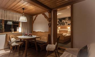 A cozy wooden cabin with a dining area and an adjoining bedroom. Cozy furnishings with warm light and traditional design.