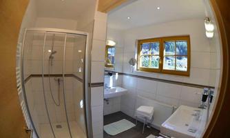 A modern bathroom with a shower and a sink. Large windows provide plenty of light and a pleasant atmosphere.