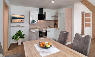 Modern kitchen with dining area and wooden details. A table with fresh fruit and a cozy atmosphere.