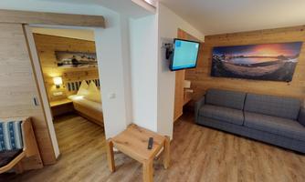 A cozy room with a sleeping area and a seating area. A television and wooden details create an inviting atmosphere.