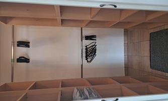 A walk-in closet with shelves and hangers. The space is well-lit and tidy.