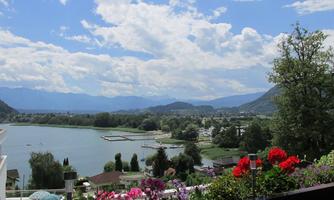 A beautiful view of a lake, surrounded by mountains and trees. Colorful flower frames in the foreground complement the landscape.