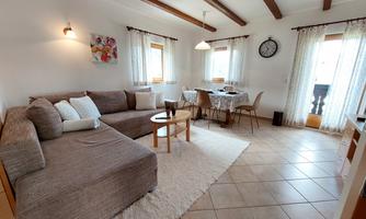 A bright living room with a comfortable sofa and a table. Large windows provide plenty of daylight and an inviting atmosphere.