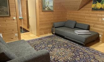 A cozy living room with wooden paneling. There is a sofa, a rug, and pictures on the wall.