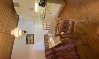 A cozy dining area with a wooden table and chairs. The kitchen is modernly furnished with white cabinets and a coffee maker.