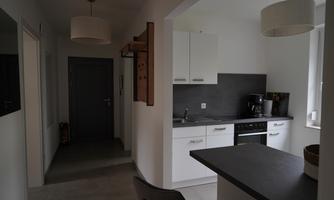A modern kitchen with white furniture and dark work surfaces. The room is bright and designed in a minimalist style.