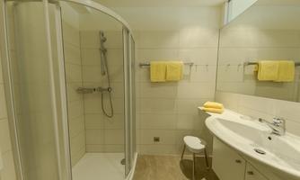 A modern bathroom with a shower cabin and bright wall tiles. Yellow towels and an elegant sink area create an inviting impression.