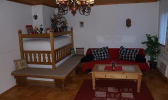 A cozy living room with a wooden bed and a red couch. The room has a wooden floor and a rustic decor.