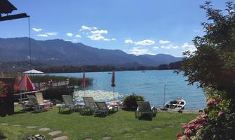 A beautiful lake with clear water and mountains in the background. Sun loungers are ready to enjoy the view.