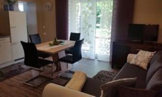 A modern living room with a comfortable couch and a dining table. Large windows let in plenty of light and provide a view outside.