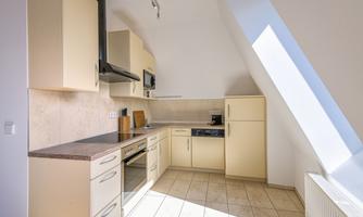 A modern kitchen with bright cabinets and a large window area. The rooms are filled with light and designed in a friendly manner.