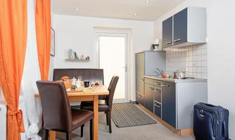 A cozy kitchen area with a table and chairs. The kitchen is modernly equipped and there is a window with a view outside.