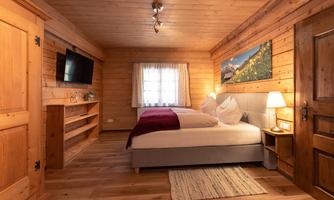 A cozy bedroom with wooden walls and a double bed. The decor radiates a warm, inviting atmosphere.