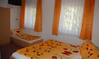 A cozy bedroom with two beds and colorful bedspreads. Large windows let in plenty of light, and the curtains in warm colors create a friendly atmosphere.