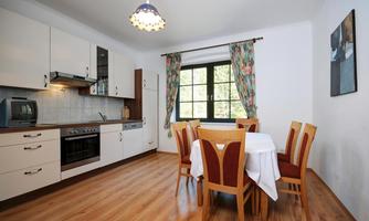 A modern kitchen with wooden flooring and a large dining table. The window brings plenty of daylight into the room.