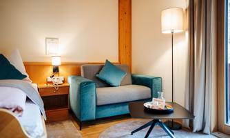 A cozy room with a blue armchair and a small table. The light is soft and the atmosphere is inviting.