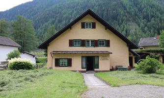 A charming house amidst green meadows and mountains. The home features a traditional design with a large garden.