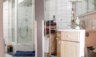 A modern bathroom with a shower cubicle and an elegant washbasin. The floor is designed with a stylish wave pattern.