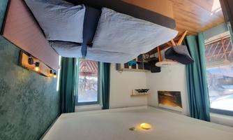 A modern room with a large double bed and a cozy seating area. Daylight streams in through the windows and there is a beautiful view outside.
