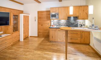 A modern kitchen with wooden cabinets and an open layout. The room has a bright and welcoming atmosphere.