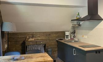 A modern kitchen with wood and metal accents. The space features a small dining nook and a cooking area.