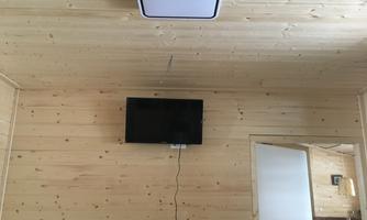 A simple room with wooden paneling. A television hangs on the wall.
