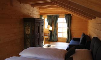 A cozy bedroom with wooden walls and two beds. Large windows let in plenty of light and offer a beautiful view.
