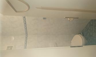 A small bathroom with a toilet and bright tiles. The space feels clean and functional.