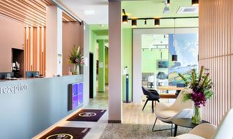 A modern hotel lobby with a friendly reception desk and stylish furniture. Fresh flowers give the space an inviting atmosphere.