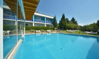 A beautiful pool with clear, blue water and a relaxed atmosphere. In the background, there are trees and lounge chairs.