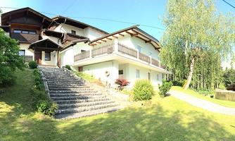 A beautiful house with two floors, surrounded by green grass and trees. The steps lead to the front door of the house.
