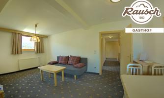 A bright and cozy room with a sofa and a table. In the background, there is an open passage to another room.