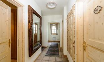 A bright hallway with wooden doors and a large mirror. The walls are painted in soft colors, creating an inviting atmosphere.