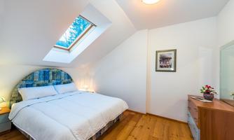 A cozy bedroom with a large double bed and a skylight. The wooden floor and simple decor give it an inviting touch.