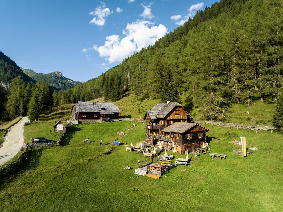 Alpenhütte mit Tischen und Bänken auf einer Bergwiese in den österreichischen Alpen