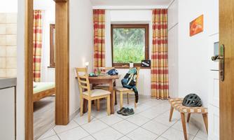 A bright room with a table and chairs. Through the window, you can see green grass and trees.