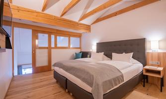 A modern bedroom with a double bed and a wooden ceiling. The room feels cozy and inviting.