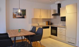 A modern kitchen with bright cabinets and an inviting dining area. The space is well-lit and has a practical layout.