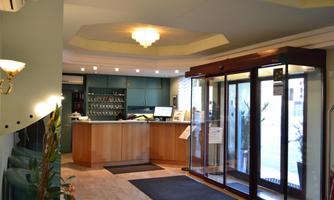 An inviting reception area with a modern reception desk. Large glass doors lead outside and provide plenty of light.