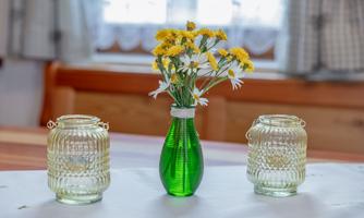 A beautiful table with a green vase and colorful flowers. Next to the vase are two transparent glass pitchers.